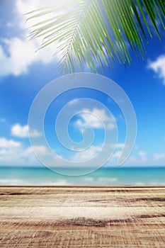 Blurred summer tropical beach background with palm leaves and table wooden.