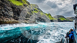 Blurred tourists observe the spectacular Vestmanna cliffs in Faroe Islands