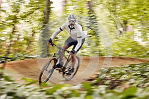 Blurred trees, cycling and man in nature training for a race, marathon or competition in forest. Fast, fitness and male