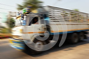 Blurred, unrecognizable trucks carry goods along highway