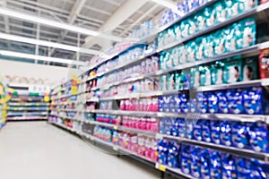 Blurred variety of bleach, fabric softener, laundry detergent on shelves at grocery store supermarket