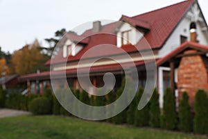 Blurred view of beautiful house with red roof outdoors. Real estate