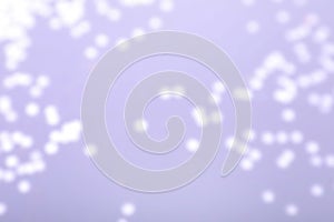 Blurred view of festive lights on light background. Bokeh effect