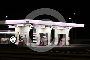 Blurred view of modern gas station with convenience store beside the road at night