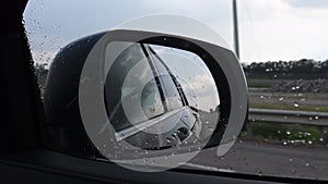 Blurred view in side mirror of fast moving car in rainy weather