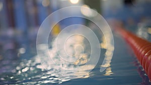 Blurred view of the sports pool. Focus on the foreground, on the lane separator. plan. Sparkling water, bokeh