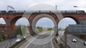 Blurred view of train on viaduct and highway traffic below