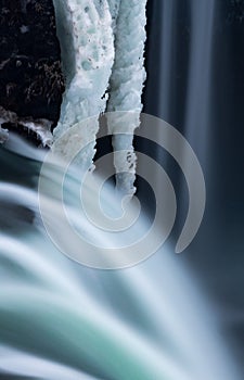 Blurred water flows from Godafoss next to frozen ice.CR2