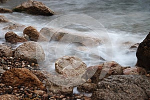 Blurred waves on wet stones of seacoast in off-season