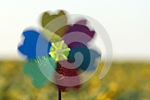 Blurred windmill toy on yellow field background. Alternative energy concept