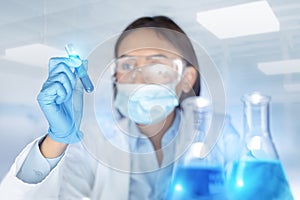 Blurred woman chemist holding a test-tube examines chemical solution in laboratory