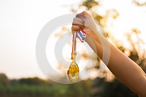 Blurred of woman hands raised and holding gold medals with Thai ribbon against blue sky background to show success in sport or