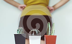 Blurred woman standing on white background with cactus and suffering from hemorrhoids