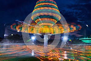 Blurred yellow and green lights of carnival ride at night during county fair