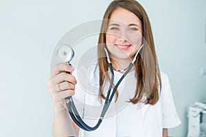 Blurred Young smiling female doctor holding her stethoscope to insinuate that it`s time for a check up in clinic on white backgro