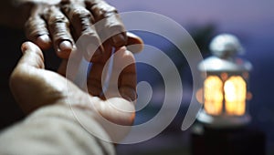 Blurry background of helping hand with light lantern on the blue background. Hands of couple, kindness and humility.