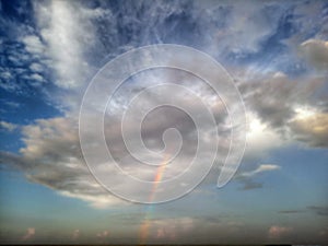 Blurry background of rainbow and the storm clouds.  Cloud human shape in spiritual imagination, blessing lights. Blue sky clouds.