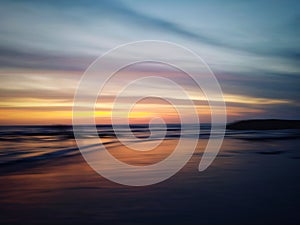 Blurry beach landscape background. Colorful sunset sunrise backgrounds. Dramatic sky colors over horizon. Blurry wave motion.