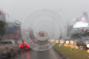 Blurry car silhouette seen through water drops on the car windshield