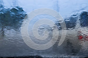 Blurry car silhouette seen through water drops on the car windshield