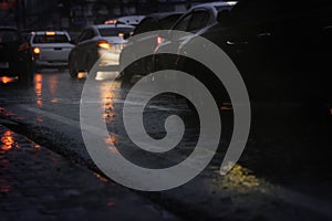 à¸´Blurry cars in a long queue on the busy city street during hard rain fall at night.