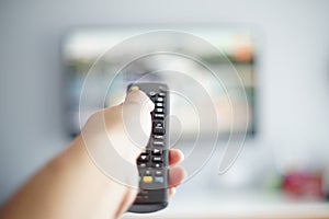 blurry Close up male hand holding remote control pointing to change the programme television in the hotel room