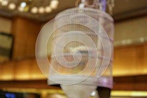 Blurry close up view of a bird in a white wooden cage as decoration in wedding party