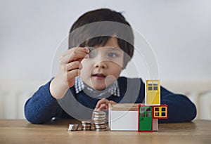 Blurry face of preschool kid showing 10 pence with smiling face, Selective focus kid boy  making stack money coins and counting