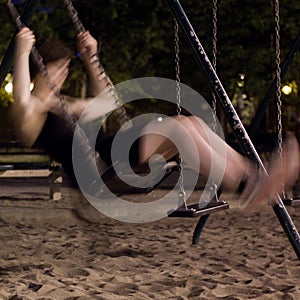 Blurry girl on a swing at night