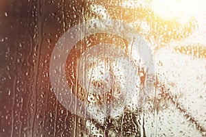Blurry image background during rain storm showers with water drop on clear glass on summer twilight bright sky day. Image use for