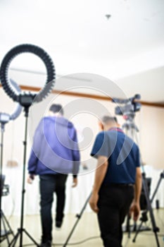 Blurry image of cameramans working with camera and blurry ring lighting in studio for broadcasting