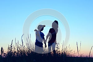 Blurry image of children playing outdoor over blue sky background. Family, childhood, friendship concept. Kids silhouettes.