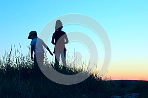 Blurry image of children playing outdoor over blue sky background. Family, childhood, friendship concept. Kids silhouettes.