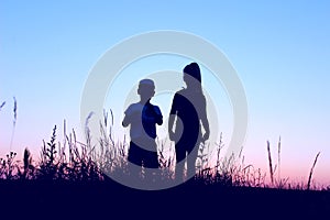Blurry image of children playing outdoor over blue sky background. Family, childhood, friendship concept. Kids silhouettes.