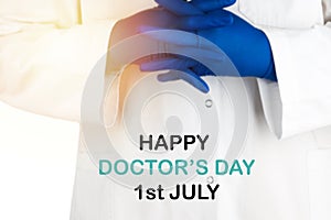 Blurry image of Doctor hands with text HAPPY DOCTOR`S DAY 1ST JULY on white background