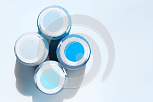 Blurry image of four cans of paint on light blue background, horizontal view. Space for text. Renovation concept.