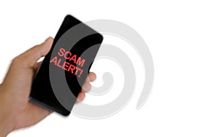 Blurry image of hand holding mobile phone with word SCAM ALERT photo