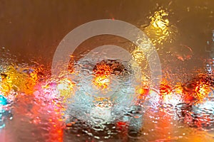 Blurry image of inside cars with bokeh lights with traffic jam and raining on night time for background usage.