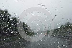 Blurry image of Rain drop falling on car windshield