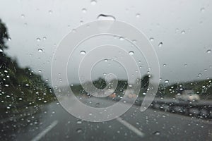 Blurry image of Rain drop falling on car windshield