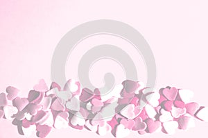 Blurry image of small colorful hearts are scattered on pink backdrop. Holidays, minimalism concept.