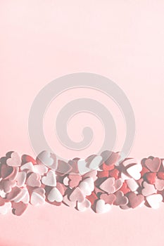 Blurry image of small colorful hearts are scattered on pink backdrop. Holidays, minimalism concept.