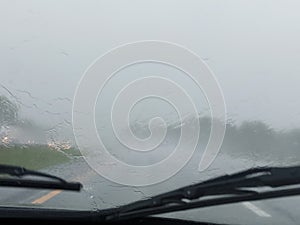 Blurry image of windshield wipers from inside of car while driving in rain