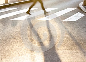 Blurry legs and shadow of a teenage girl crossing the city street