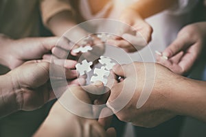 The blurry light design background of people hands assembling jigsaw puzzle,searching for right match,teamwork support