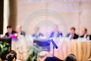 Blurry of microphone with chairman of the meeting and executive committee background in auditorium for shareholders meeting or photo