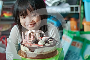 Blurry photo of a chubby Asian little girl celebrating her birthday at home. Happy and jovial in front of the cake. Soft focus