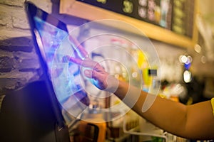 Blurry picture of cashier is making order on touch screen of computer in cafe or store