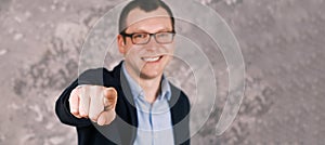 Blurry portrait of a young confident smiling modern businessman in glasses in a suit against the background of a gray