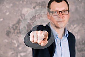 Blurry portrait of a young confident smiling modern businessman in glasses in a suit against the background of a gray